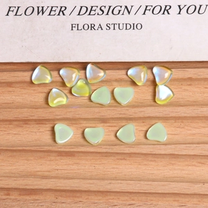 Macro shot of aurora heart-shaped glass nail art charms on a grooved wooden tray