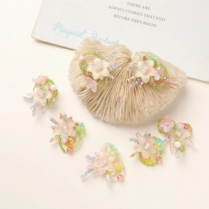 Handmade gradient glass flower pendants with pearls and beads on a seashell display