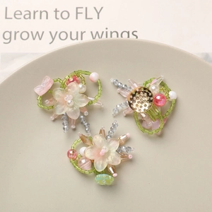 Close-up of handmade beaded glass flower charms in soft pink and green tones