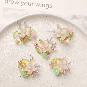Handmade gradient glass flower charms for DIY jewelry making on white ceramic plate
