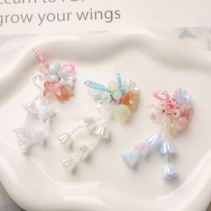 Detailed close-up of handmade beaded lily of the valley pendants on a white ceramic tray