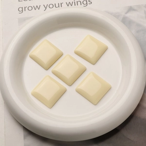 Macro detail of five cream-colored square resin cabochons for DIY earring and hair accessories