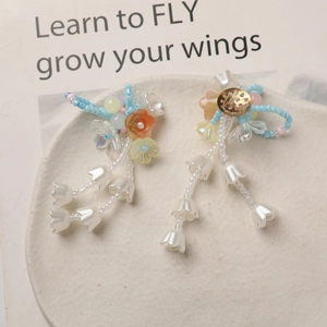 Detail of handmade lily of the valley earrings with orange resin flowers and blue beads