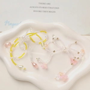 Macro detail of a colorful beaded bow charm with delicate flower pendants in a ceramic tray