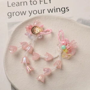 Close-up of pink lily of the valley beaded earrings on a white textured ceramic plate