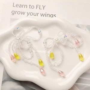 Close-up of beaded bow pendant with long colorful tassels on a white cloud tray