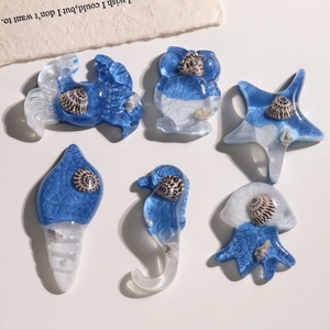 Detailed view of six-piece blue glitter resin ocean charms with real seashells