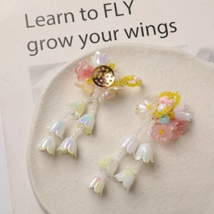 Close-up of lily of the valley earrings with iridescent resin petals and gold base