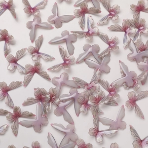 Detailed macro view of purple and pink gradient resin butterfly charms with silver glitter