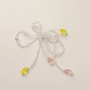 Detail of beaded crystal bow pendant with pastel teardrop charms and pearl center