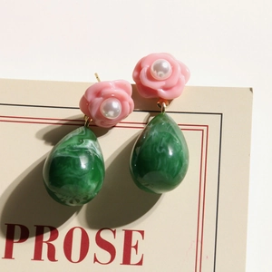 Detailed macro of floral resin earrings with pink rose and green marbled teardrop pendant