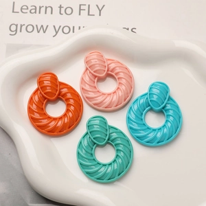 Boucles d'oreilles créoles nervurées en résine orange, rose, cyan et bleu sur plateau