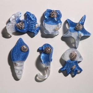 Macro detail of blue resin starfish and seahorse charms with embedded shell fragments