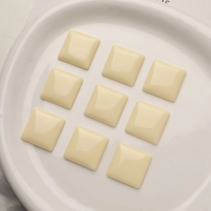 Close-up of nine cream square resin cabochons for DIY earring and hair jewelry making