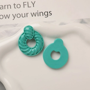 Détail de boucles d'oreilles créoles en résine turquoise à texture spirale sur plateau