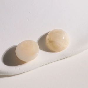 Détails macro d'accessoires ronds en résine crème avec texture marbrée sur pierre