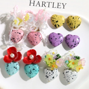 Close-up of five colorful heart-shaped resin bead earrings with black speckled texture