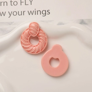Vue détaillée de boucles d'oreilles rondes en résine rose avec texture spirale en 3D