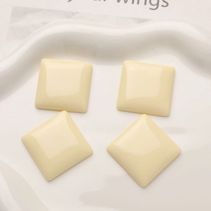 Detail of square resin flatback charms in cream color with a glossy finish on a tray