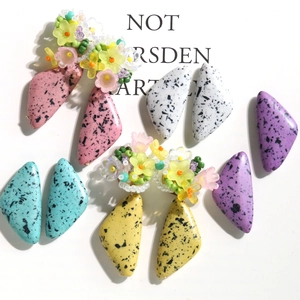 Macro shot of triangle turquoise beads with ink splatter and colorful resin floral details