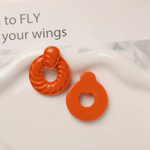 Détail macro de boucles d'oreilles en résine orange avec texture en spirale