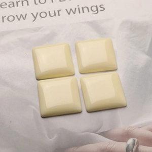 Flat lay of four cream square resin patches for DIY jewelry making and hair accessories