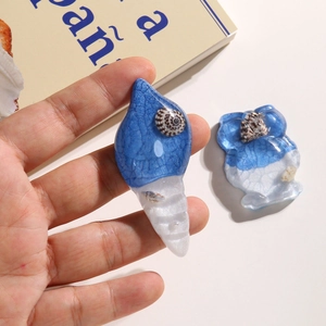 Close-up of resin shell and owl charms with ice-crack texture and pearl details