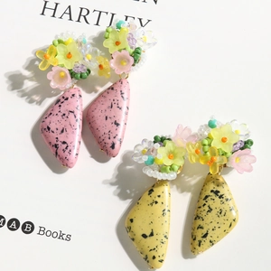 Close-up of handmade floral earrings with pink and yellow ink-splatter petals and beads