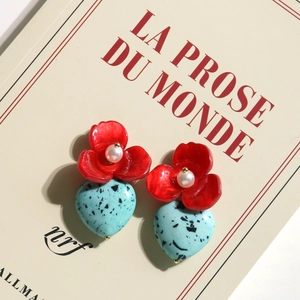 Red flower and blue heart turquoise drop earrings displayed on a French book cover