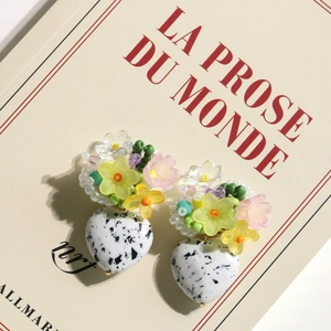 Artistic turquoise heart earring with resin flowers placed on a French book page