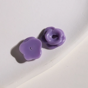 Macro shot of small purple resin flower charms showing front petals and flat back