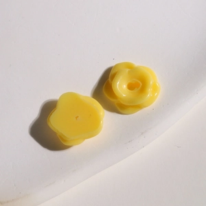 Macro detail of small yellow resin flower beads with back holes for DIY jewelry making