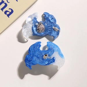 Detailed macro view of resin wave charms with embedded shells for DIY ocean crafts
