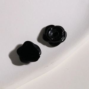 Macro shot of black resin rose charm showing glossy petal texture and 3D floral details
