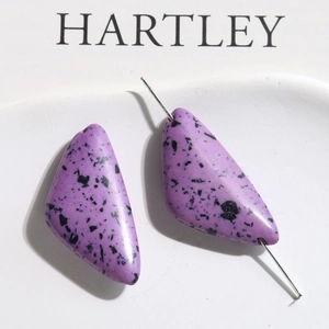 Macro detail of purple triangle marble-patterned beads with silver pin for DIY jewelry