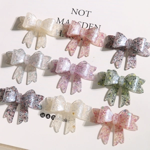 Close-up of colorful bow-shaped resin charms with glitter and sequins for DIY jewelry
