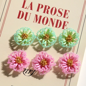 Macro detail of handmade beaded pink and green floral earrings on vintage card