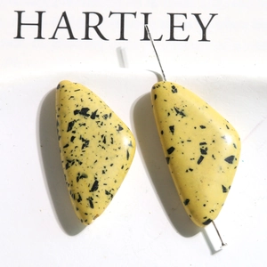 Macro detail of yellow triangular turquoise beads with black splatter for DIY jewelry
