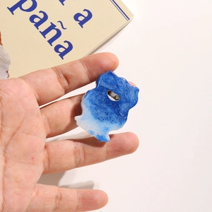 Close-up of a blue and white gradient resin cat charm with glitter for DIY projects