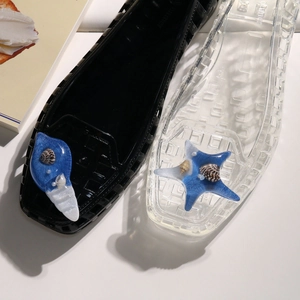 Detail of jelly shoes with blue resin charms containing real shells and white pearls