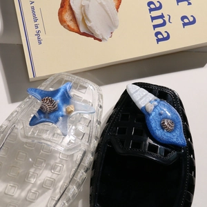 Detail of blue starfish and conch shoe charms with shell fragments on garden clogs
