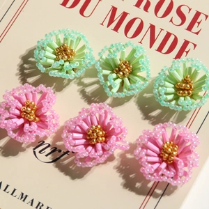 Detailed view of handmade beaded floral charms in pink and green for DIY jewelry