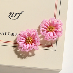 Close-up of handmade pink beaded flower earrings with gold bead centers on card