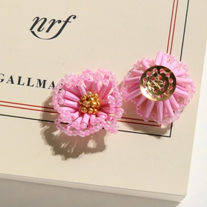 Close-up of pink beaded flower earrings with intricate woven petals and gold centers