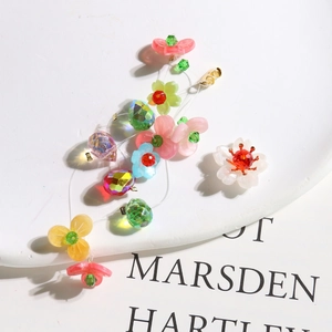 Detail of handmade crystal woven flower earrings with colorful resin beads and tassels