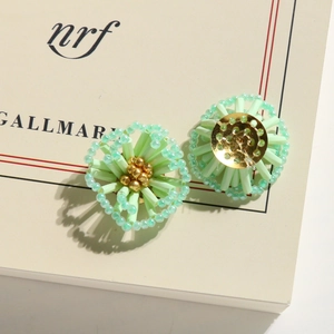 Detailed view of light green beaded flower earrings with gold center and metal base
