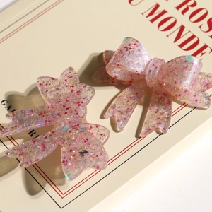 Detail of pink resin butterfly bow hair clip with glitter sequins on vintage book