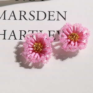 Top view of sweet pink woven flower earrings with gold bead centers on white card