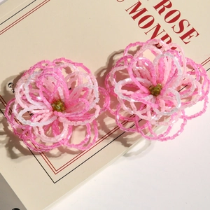Close-up of pink gradient beaded flower charms with transparent petals and amber center