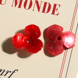 Dettaglio macro di ciondoli a tulipano in acrilico rosso con finiture lucide e perlate